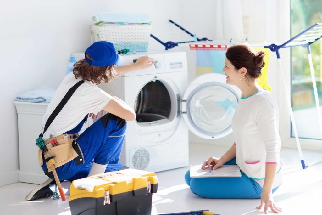 a technician repairing a washer while woman is watching - appliance repair service Pittsburgh
