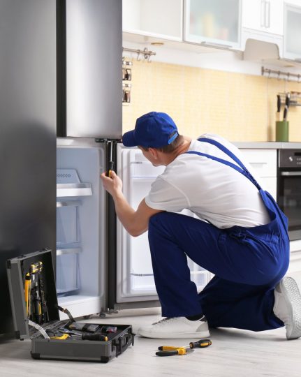 a technician repairing a refrigerator - Next Door Appliance Repair Pittsburgh